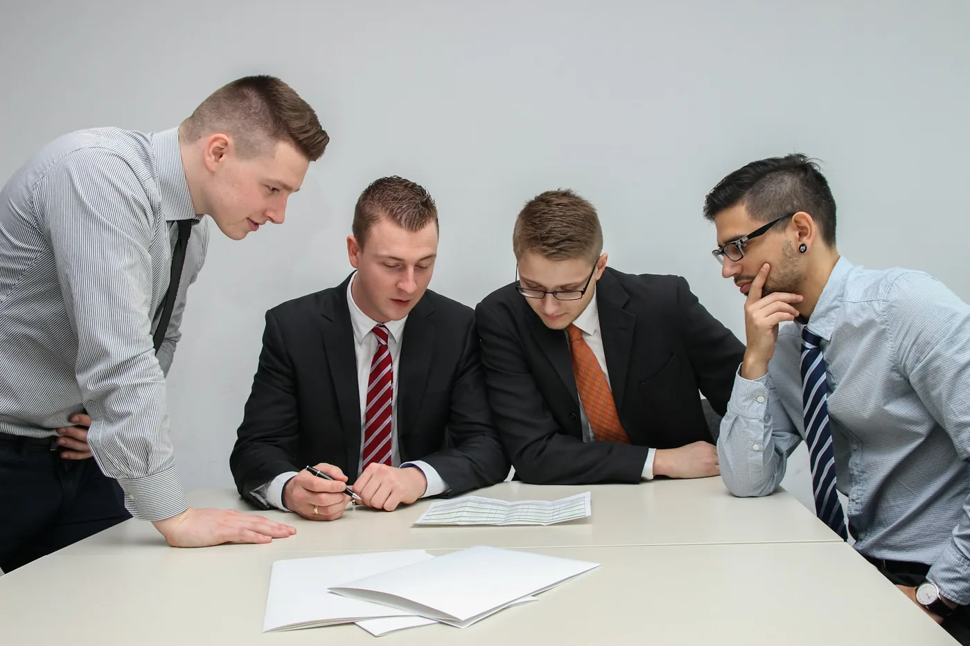 Vier Fuehrungskraefte pruefen gemeinsam Unterlagen vor einer Entscheidung